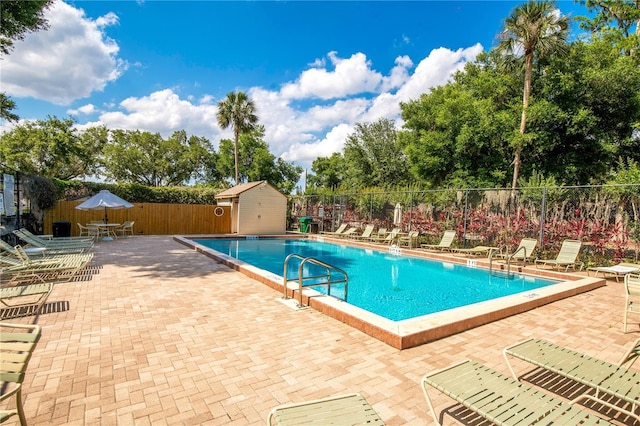 pool with fence, a patio, and an outbuilding