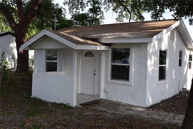 view of front of house featuring stucco siding and roof with shingles