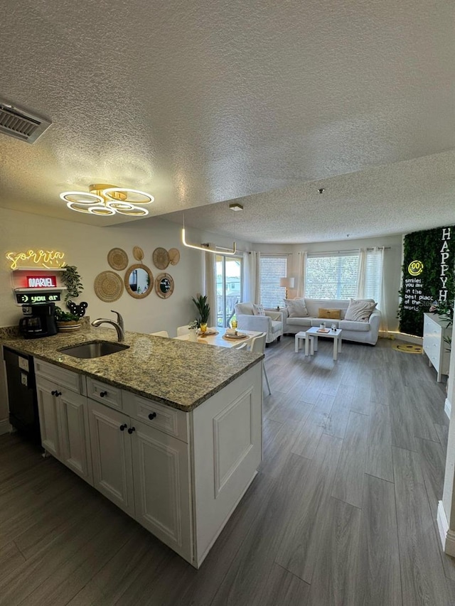 6403 Parc Corniche Dr Unit 4308, Orlando, FL 32821 - kitchen featuring dark wood-style flooring, a textured ceiling, visible vents, a sink, and a peninsula