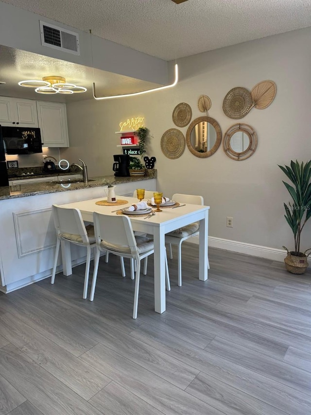 6403 Parc Corniche Dr Unit 4308, Orlando, FL 32821 - dining area featuring visible vents, a textured ceiling, light wood finished floors, and baseboards
