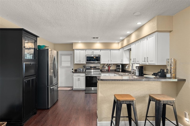 195 E Faith Ter, Maitland, FL 32751 - kitchen featuring appliances with stainless steel finishes, a sink, a textured ceiling, dark wood finished floors, and a peninsula