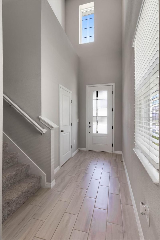 entryway with baseboards, a high ceiling, and stairway