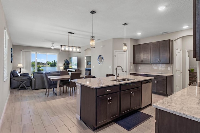 kitchen featuring a sink, arched walkways, dark brown cabinetry, and dishwasher