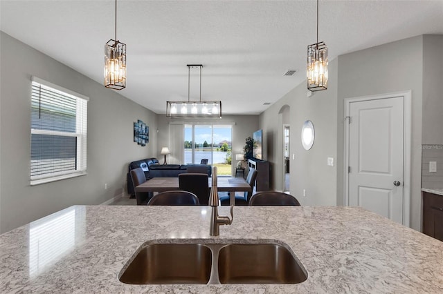 kitchen featuring a sink, light stone countertops, a notable chandelier, and open floor plan