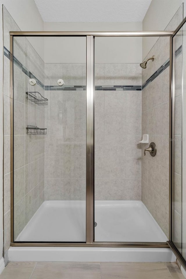 bathroom with a shower stall and tile patterned flooring