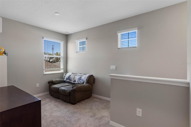 sitting room featuring light colored carpet, baseboards, and a healthy amount of sunlight