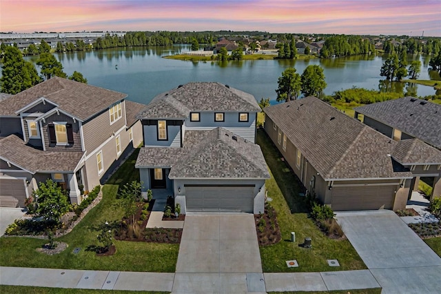 aerial view at dusk featuring a water view and a residential view