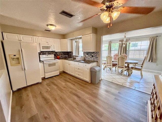 kitchen with white cabinetry, decorative backsplash, dark countertops, visible vents, and white appliances