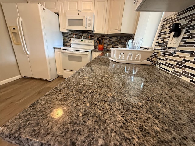 kitchen with dark stone countertops, white cabinetry, white appliances, and backsplash