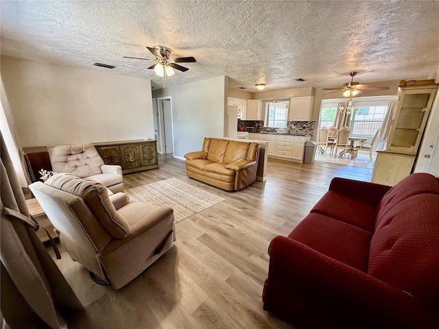 living room with a ceiling fan and a textured ceiling