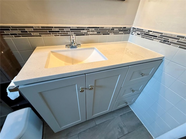 bathroom with vanity, wainscoting, and tile walls