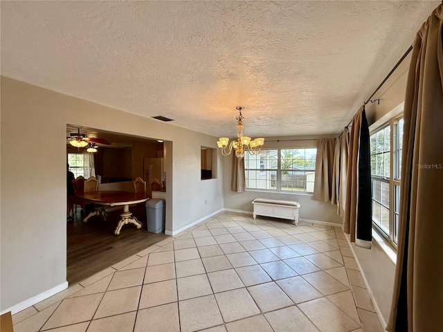unfurnished dining area featuring baseboards, visible vents, a textured ceiling, and light tile patterned flooring