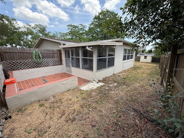 rear view of house featuring a storage shed, a sunroom, a fenced backyard, and a patio area
