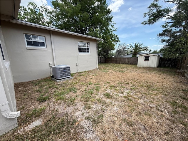 view of yard featuring a storage shed, central AC, an outdoor structure, and a fenced backyard