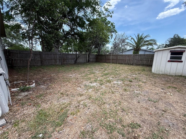 view of yard with a storage shed, a fenced backyard, and an outdoor structure