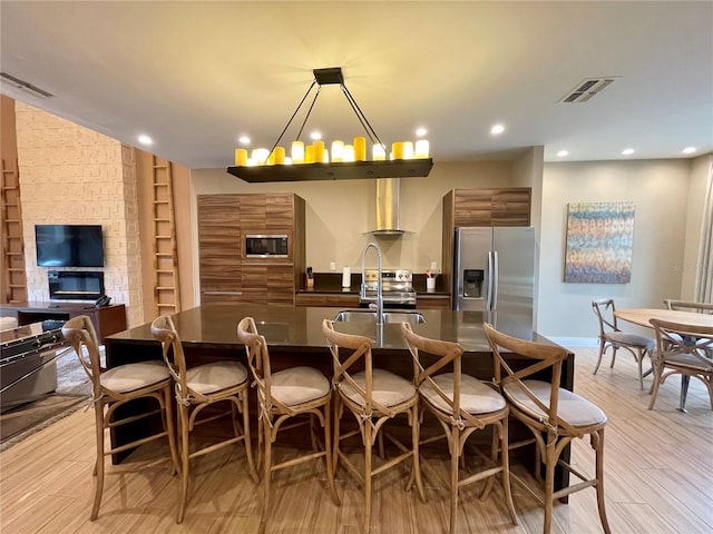 kitchen featuring a kitchen breakfast bar, brown cabinets, dark countertops, visible vents, and stainless steel appliances
