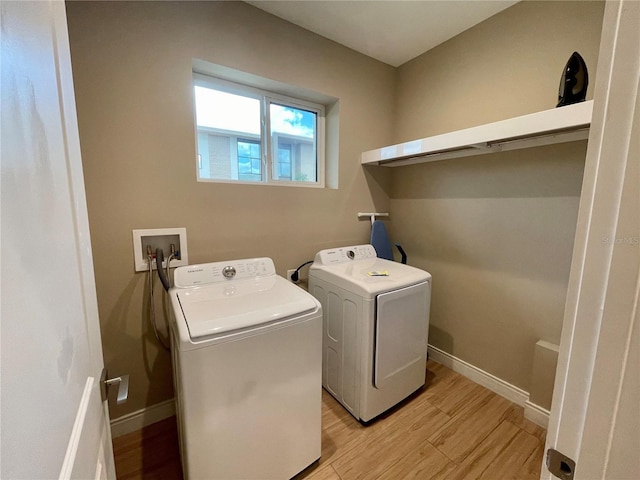 clothes washing area with light wood-style floors, washing machine and clothes dryer, laundry area, and baseboards