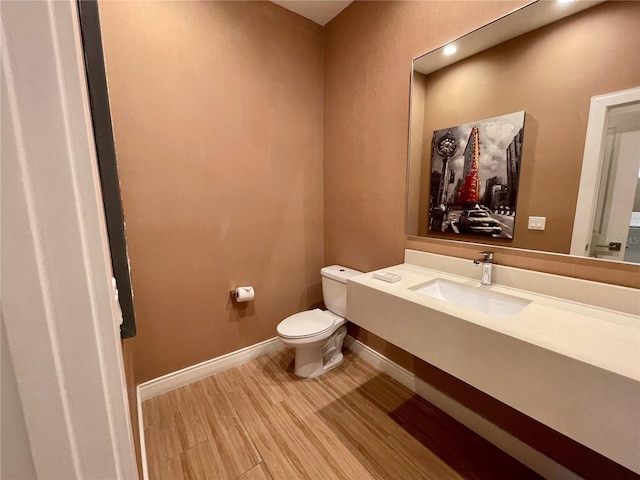 bathroom with baseboards, wood finished floors, toilet, and vanity