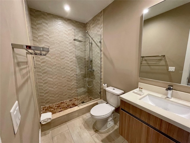 full bathroom featuring toilet, a tile shower, tile patterned flooring, and vanity