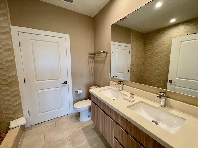 bathroom with tile patterned floors, toilet, double vanity, and a sink