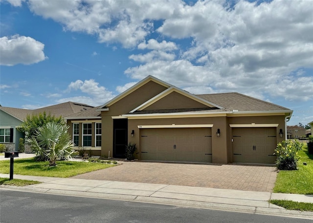 274 Brunswick Dr, Davenport, FL 33837 - ranch-style house featuring stucco siding, decorative driveway, an attached garage, and a shingled roof