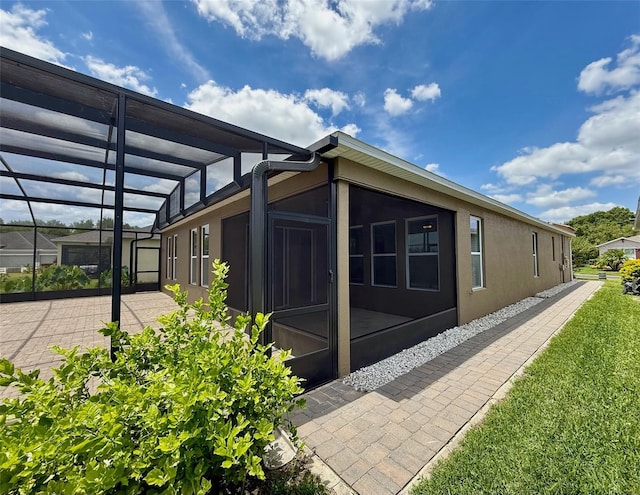 274 Brunswick Dr, Davenport, FL 33837 - view of home's exterior featuring stucco siding, glass enclosure, and a patio