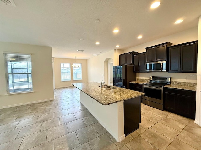 274 Brunswick Dr, Davenport, FL 33837 - kitchen with appliances with stainless steel finishes, a sink, a kitchen island with sink, light stone countertops, and arched walkways