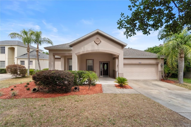 view of front of property featuring an attached garage, a shingled roof, stucco siding, and driveway