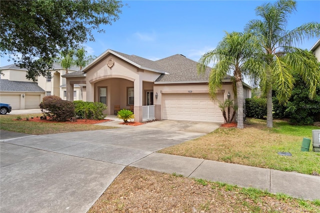 view of front of property with a garage, a front yard, roof with shingles, stucco siding, and concrete driveway