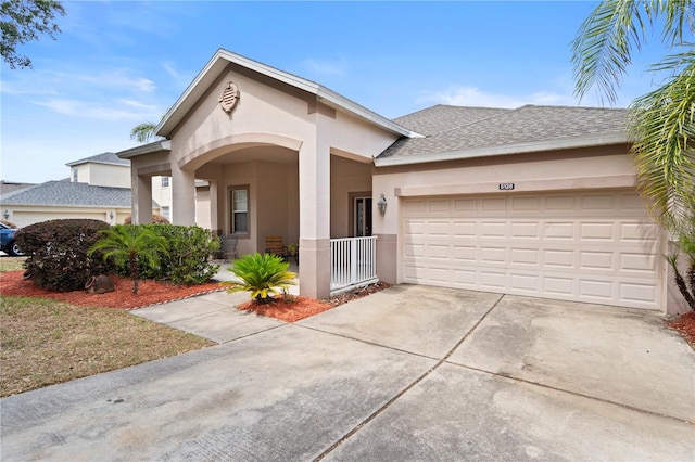 view of front of property featuring covered porch, driveway, an attached garage, a shingled roof, and stucco siding