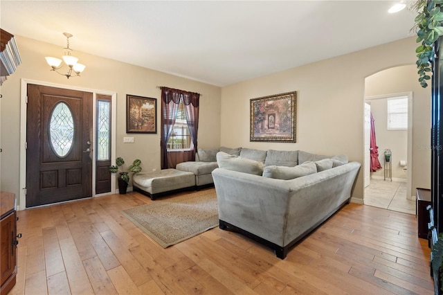 living area with arched walkways, plenty of natural light, and light wood finished floors