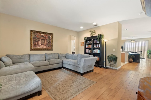 living room featuring recessed lighting, arched walkways, baseboards, and light wood finished floors
