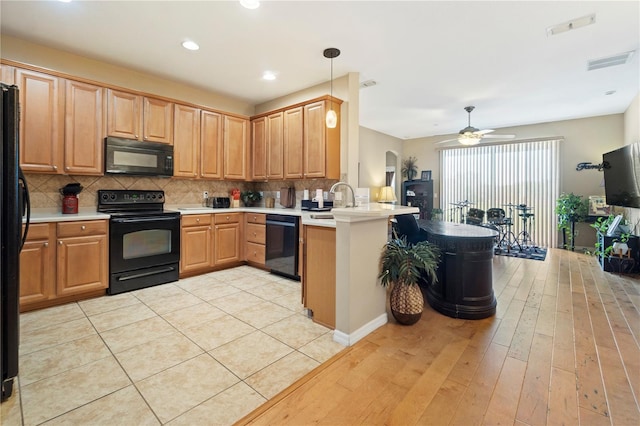 kitchen with a peninsula, visible vents, black appliances, and light wood-style floors