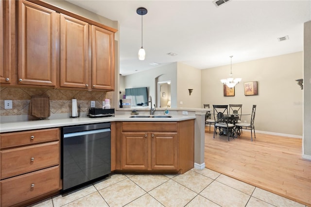kitchen featuring a sink, dishwasher, a peninsula, decorative backsplash, and visible vents