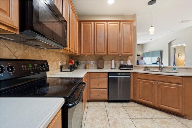 kitchen with a sink, light countertops, brown cabinetry, decorative backsplash, and black appliances