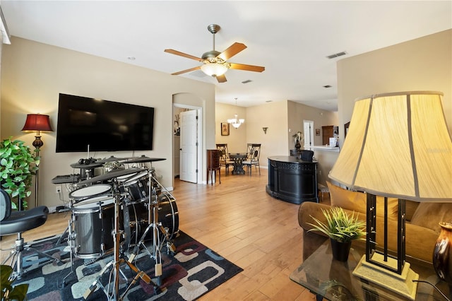 living area with visible vents, ceiling fan with notable chandelier, and hardwood / wood-style floors