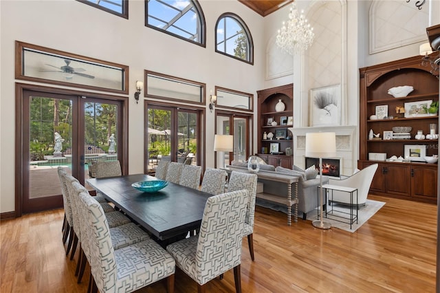 1716 Greystone Ct, Longwood, FL 32779 - dining area featuring french doors, built in shelves, light wood finished floors, a warm lit fireplace, and a high ceiling