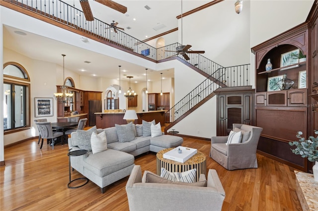 1716 Greystone Ct, Longwood, FL 32779 - living area featuring a high ceiling, light wood finished floors, ceiling fan with notable chandelier, baseboards, and stairway