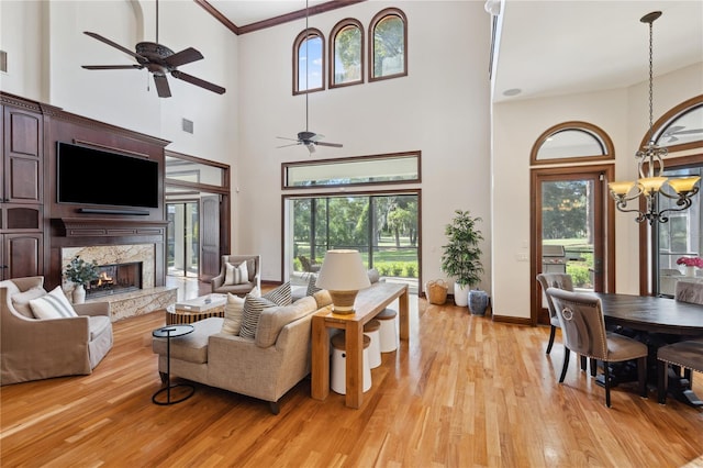 1716 Greystone Ct, Longwood, FL 32779 - living area featuring plenty of natural light, a towering ceiling, a high end fireplace, ceiling fan with notable chandelier, and light wood finished floors