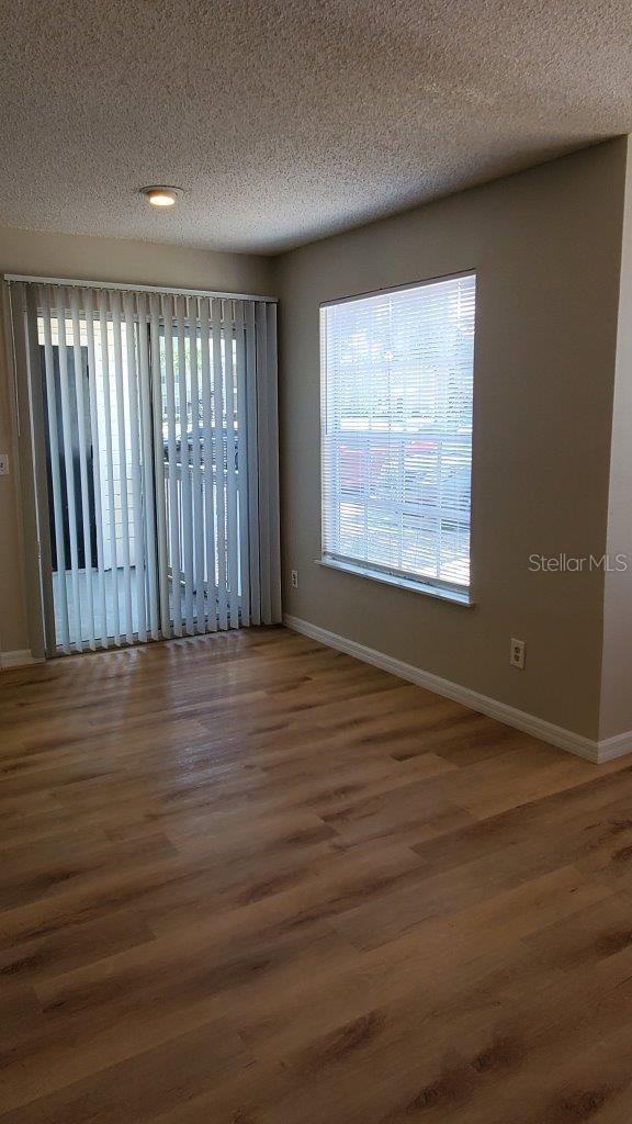 1071 S Hiawassee Rd Unit 1211, Orlando, FL 32835 - unfurnished room with baseboards, a textured ceiling, and wood finished floors