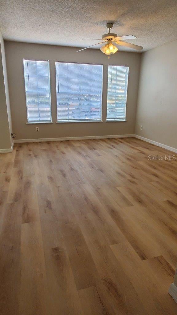 1071 S Hiawassee Rd Unit 1211, Orlando, FL 32835 - empty room featuring light wood-style floors, a textured ceiling, and plenty of natural light