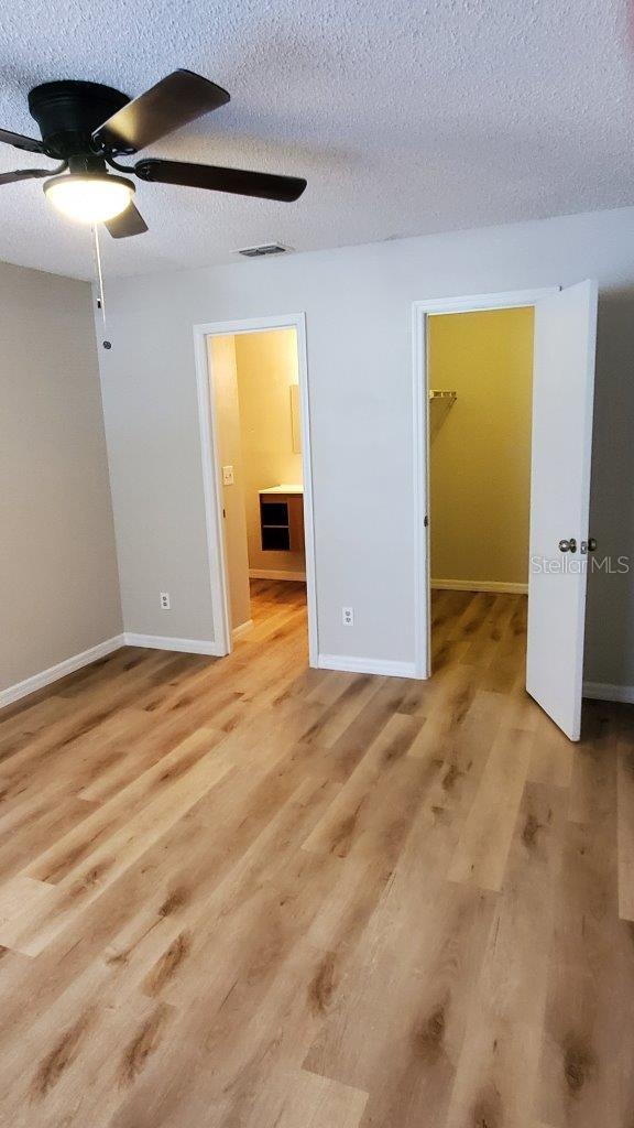 1071 S Hiawassee Rd Unit 1211, Orlando, FL 32835 - unfurnished bedroom with baseboards, visible vents, a walk in closet, and light wood-type flooring