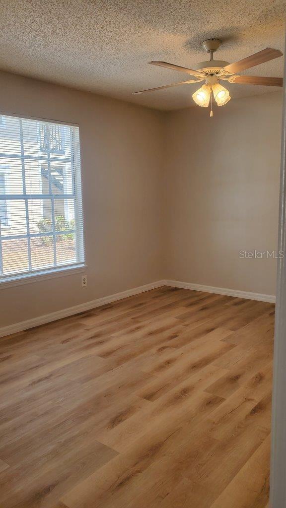 1071 S Hiawassee Rd Unit 1211, Orlando, FL 32835 - empty room with light wood-style floors, a ceiling fan, baseboards, and a textured ceiling