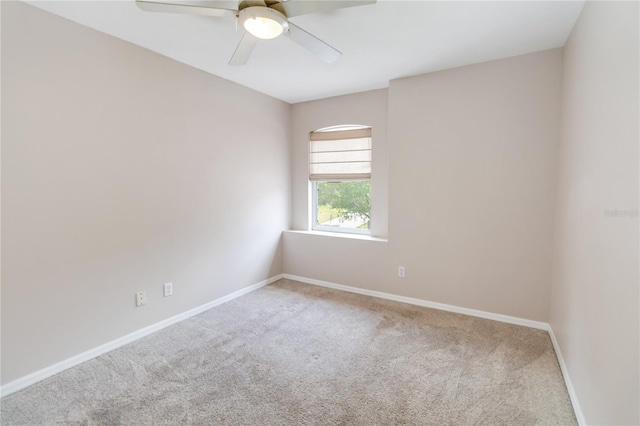 carpeted spare room featuring baseboards and ceiling fan
