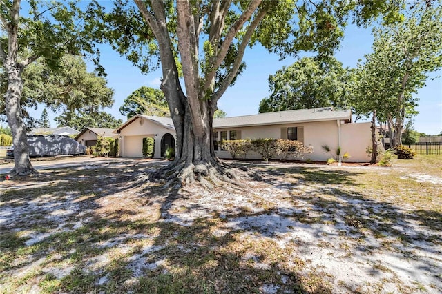 single story home with an attached garage, stucco siding, and fence