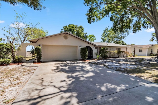 ranch-style house featuring concrete driveway, stucco siding, and an attached garage