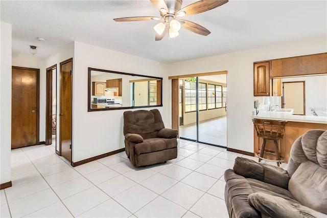living area with light tile patterned floors, baseboards, and a ceiling fan