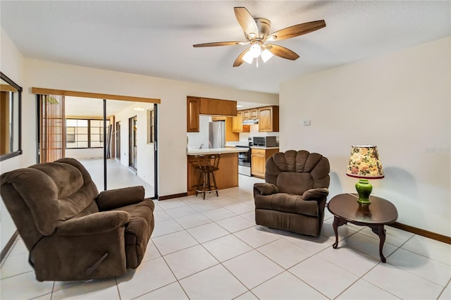 living room featuring baseboards, ceiling fan, and light tile patterned flooring
