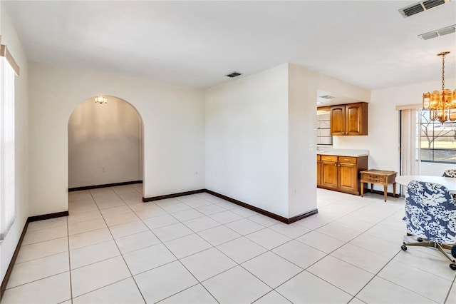 empty room featuring visible vents, arched walkways, and an inviting chandelier