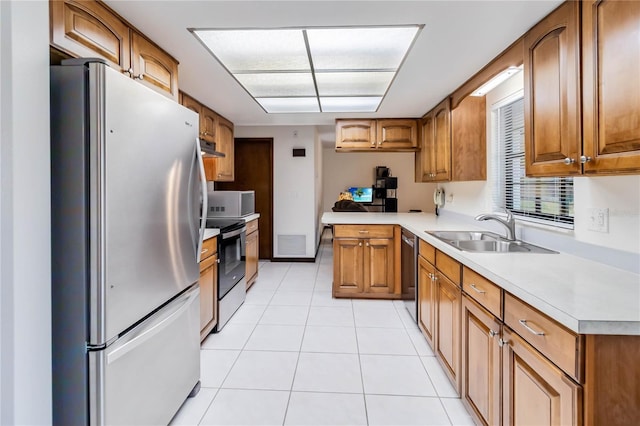 kitchen with a sink, light tile patterned floors, stainless steel appliances, and brown cabinets